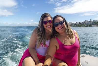 Women in bikinis on top of a boat against the sea in the background. 