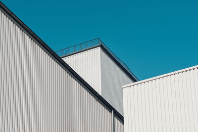 Low angle view of industrial building against clear blue sky