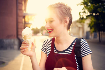 Young woman holding ice cream in city