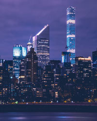 River against illuminated buildings in city at night