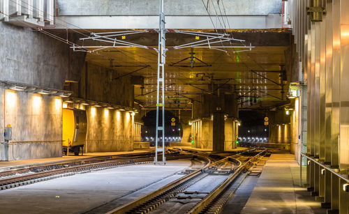 Illuminated railroad tracks amidst buildings