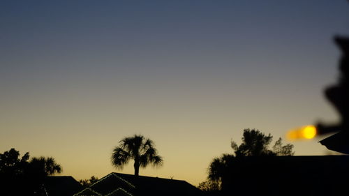 Silhouette trees and buildings against clear sky during sunset