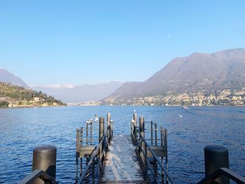 Pier over sea against clear blue sky