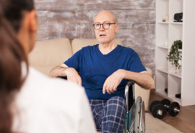 Senior man sitting on wheelchair while talking with doctor