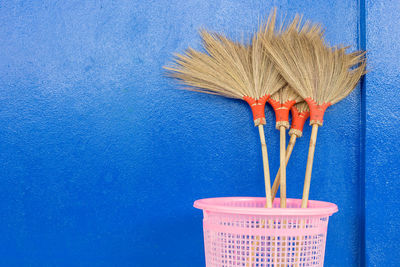 Close-up of broom in container by wall