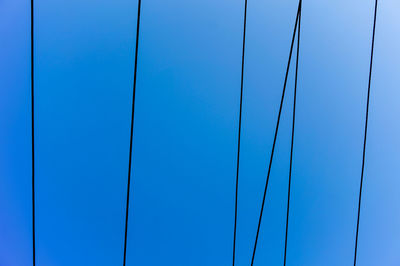 Directly below shot of cables against blue sky