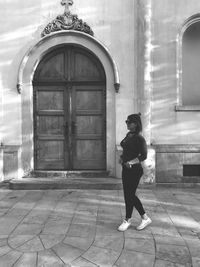 Full length side view of woman standing against building