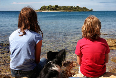 Rear view of woman with dog on sea