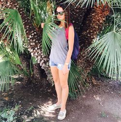 Full length of woman standing by palm tree