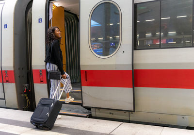 Side view of woman entering train at railroad station platform