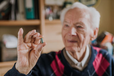 Smiling senior man holding capsule at home