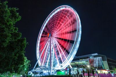 Low angle view of illuminated ferris wheel against sky at night