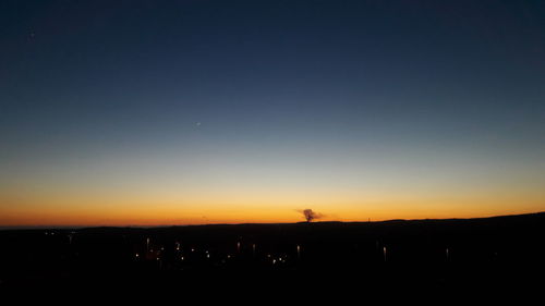 Scenic view of silhouette field against sky at sunset