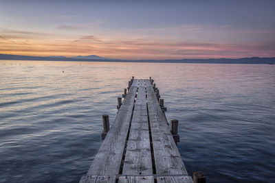 Wooden pier over lake against sky during sunset