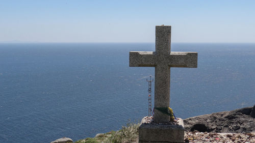 Cross on sea against clear sky