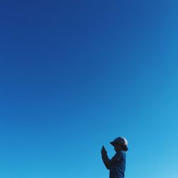 Low angle view of people standing against clear blue sky