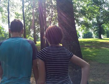 Rear view of woman standing by tree trunk