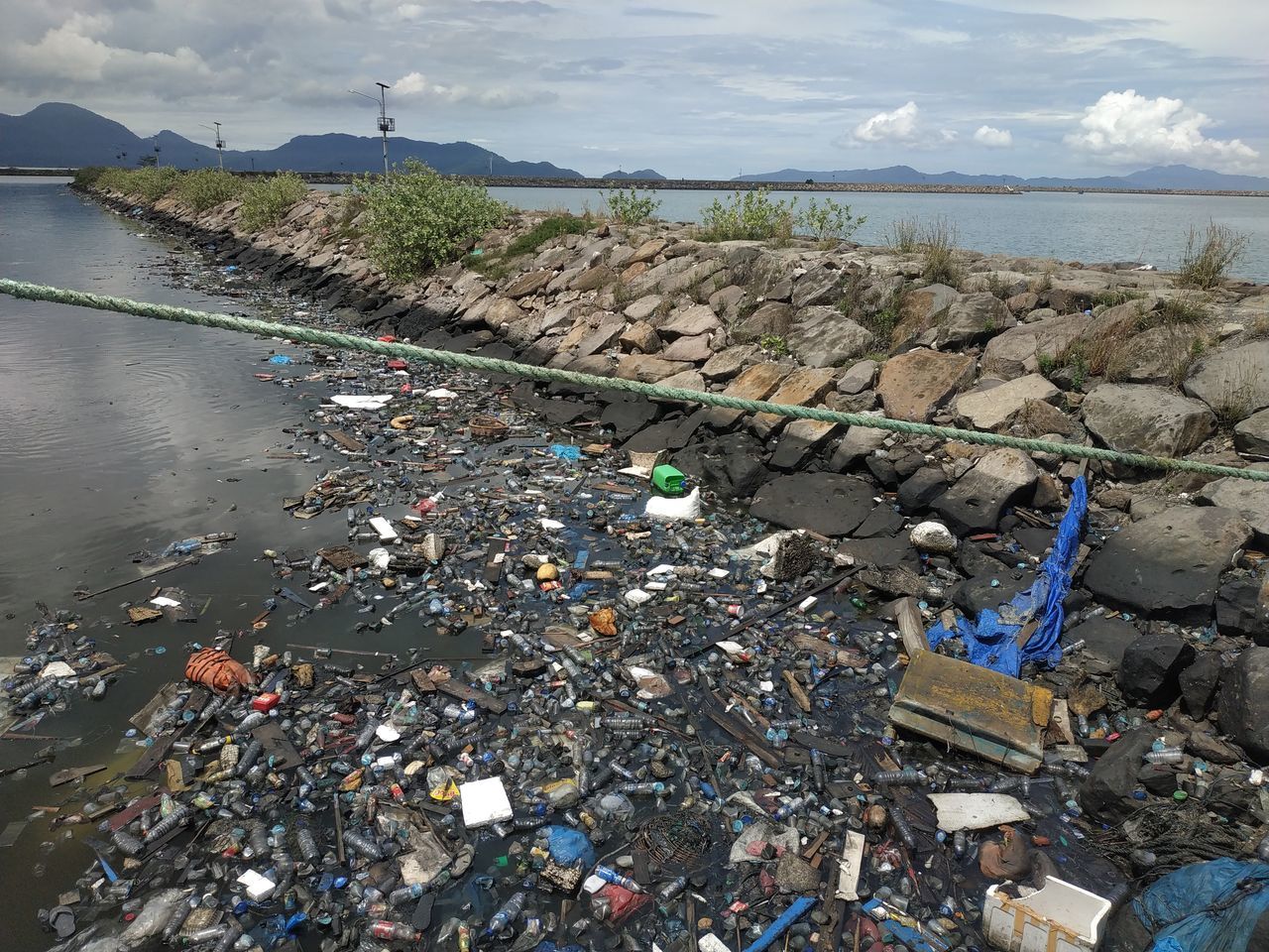 HIGH ANGLE VIEW OF GARBAGE ON SHORE AGAINST SKY