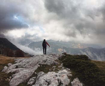 Rear view of man standing on mountain against sky