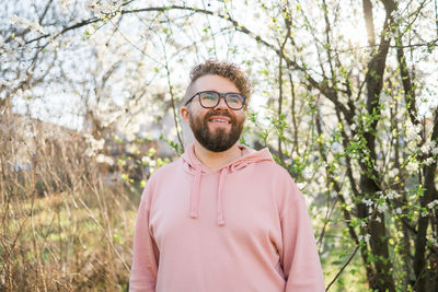 Portrait of young man wearing sunglasses standing against trees