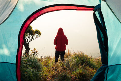 Rear view of man standing on field seen through tent