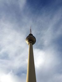 Low angle view of communications tower against cloudy sky