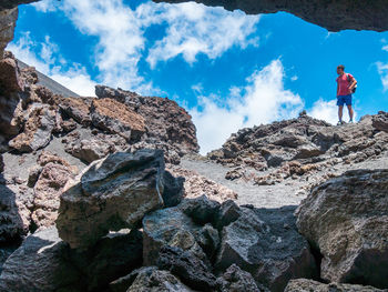 Low angle view of man standing on cliff against sky