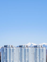 Buildings in city against clear blue sky