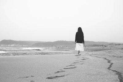 Full length of woman standing on shore against clear sky