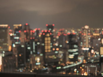 Defocused image of illuminated cityscape against sky at night