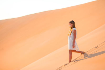 Young woman standing on sand dune in desert