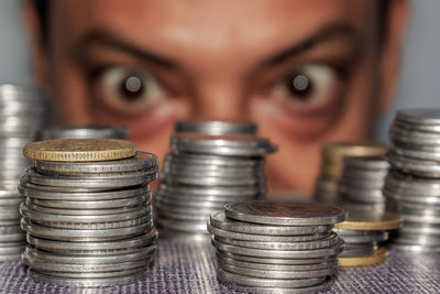 Close-up of coins stacks on table with man looking