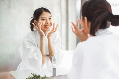 Smiling young woman using smart phone at home