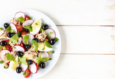 Nicoise salad with tuna, egg, cherry tomatoes and black view, copy space