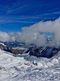 Aerial view of snowcapped mountains against blue sky