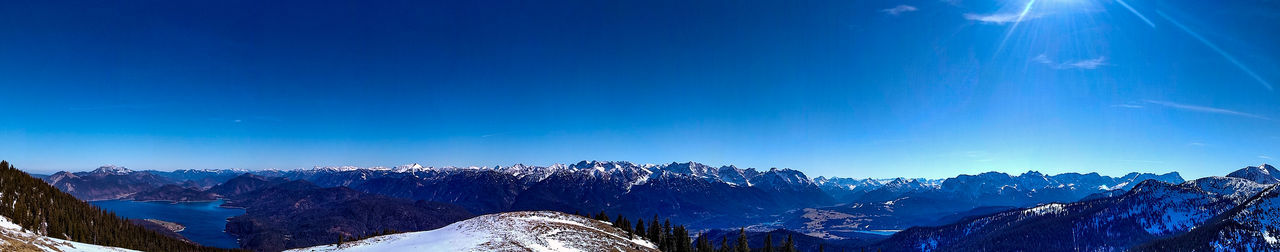 Panoramic view of snowcapped mountains against blue sky