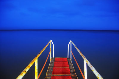 Close-up of railing by sea against clear blue sky