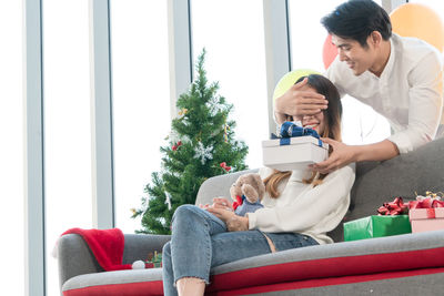 Friends looking away while sitting on sofa