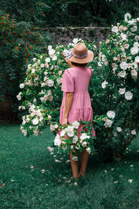 Rear view of woman standing by pink flowering plants