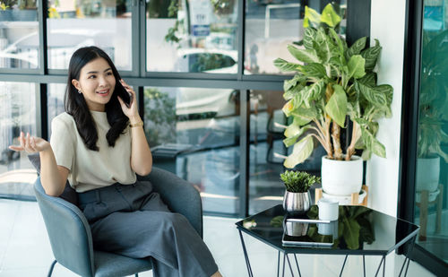Young woman using mobile phone while sitting at home