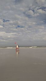Man sitting on beach against sky