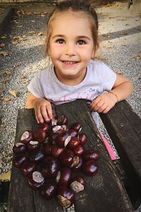 High angle view of smiling girl with chestnuts on wooden table