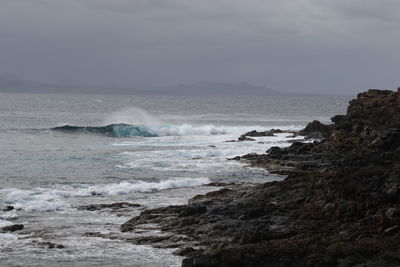 Scenic view of sea waves splashing against sky