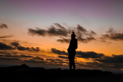 Silhouette man standing against orange sky