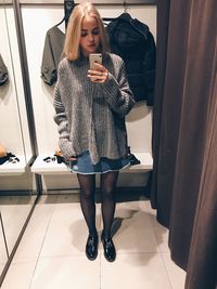 Full length of young woman taking selfie with smart phone while standing in store