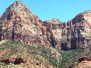 Low angle view of rocky mountain against blue sky