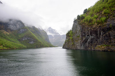 Scenic view of river by mountains against sky