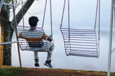 Rear view of man sitting on seat in park