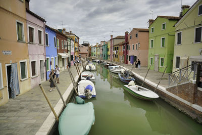 Boats moored on canal amidst buildings in city