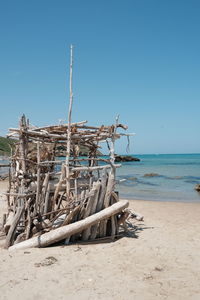 Wooden posts on beach against clear blue sky